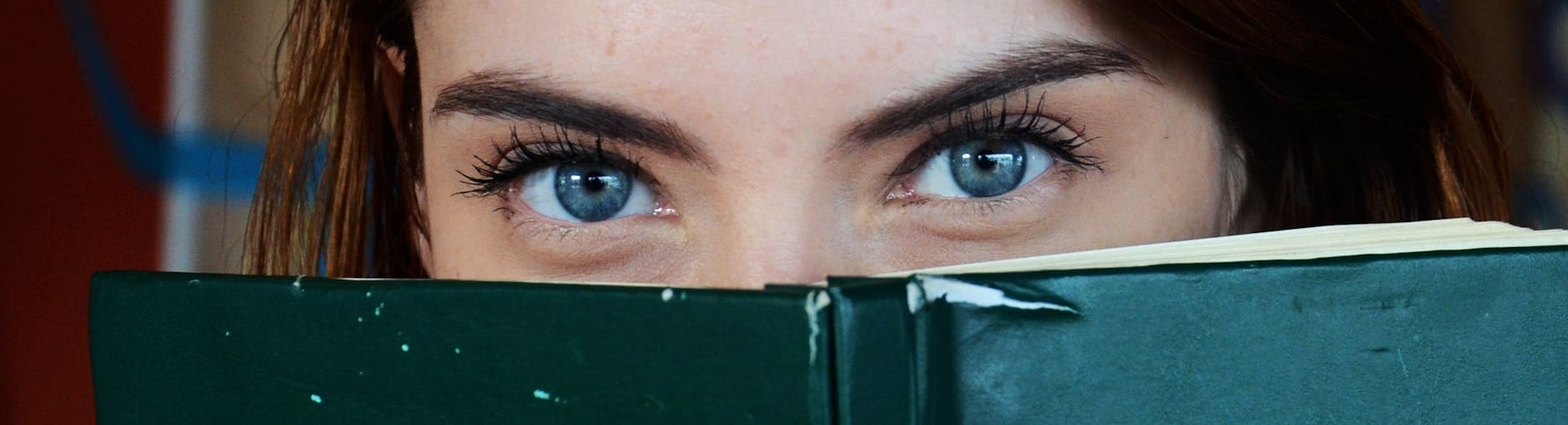 woman covering her face with green book