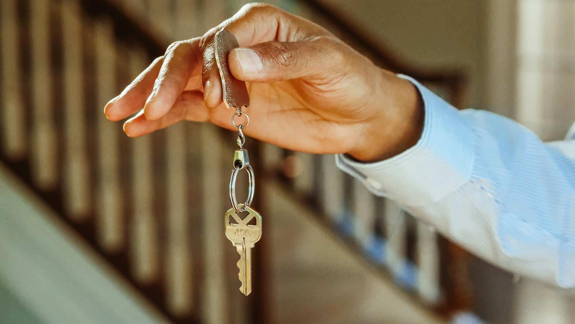 person holding a silver keychain with a key