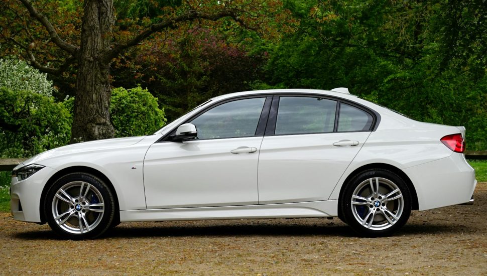white bmw sedan parked beside tree