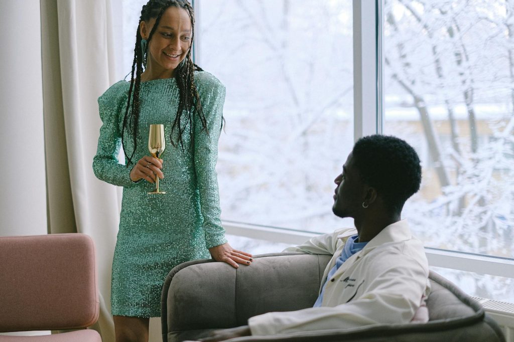 a woman holding a drink beside a sitting man