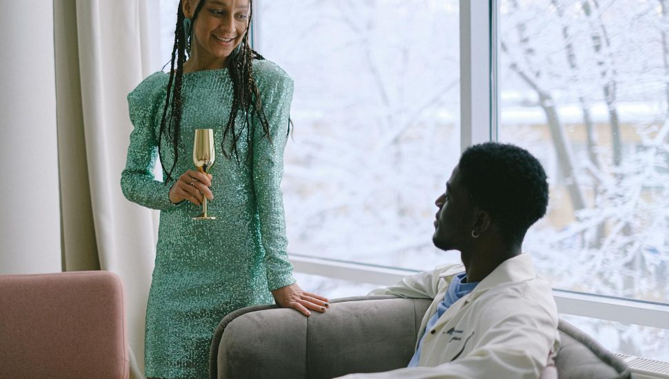 a woman holding a drink beside a sitting man