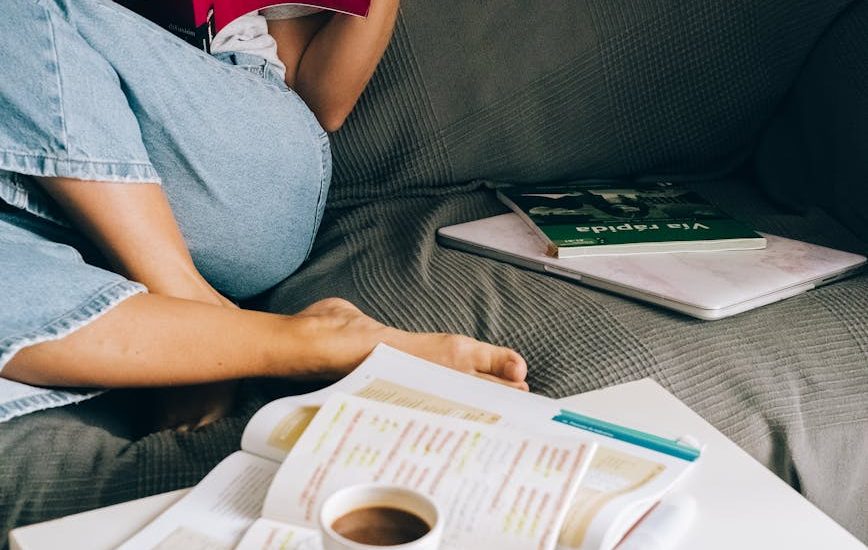 a woman sitting on the couch while reading a book