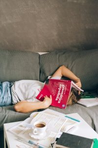 a person with a book on the face lying down the couch