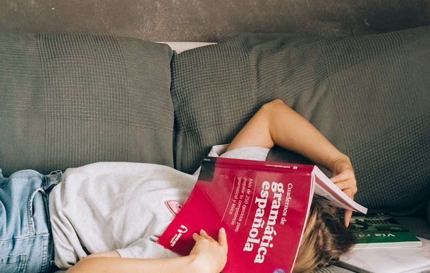 a person with a book on the face lying down the couch