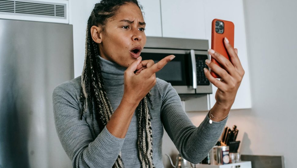expressive young black lady arguing during video conversation on smartphone