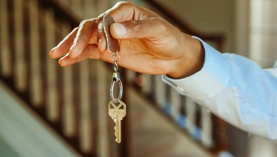 person holding a silver keychain with a key