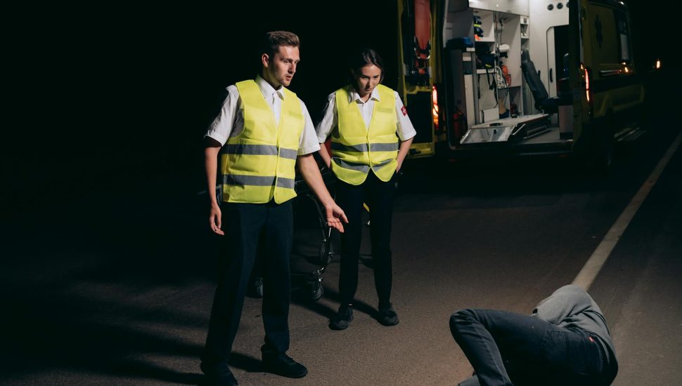 paramedics looking at the person lying on the street