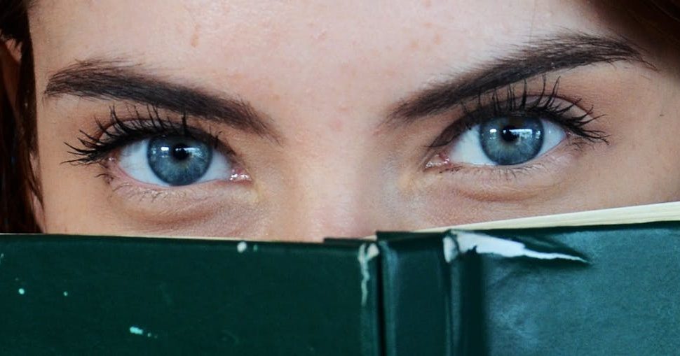 woman covering her face with green book