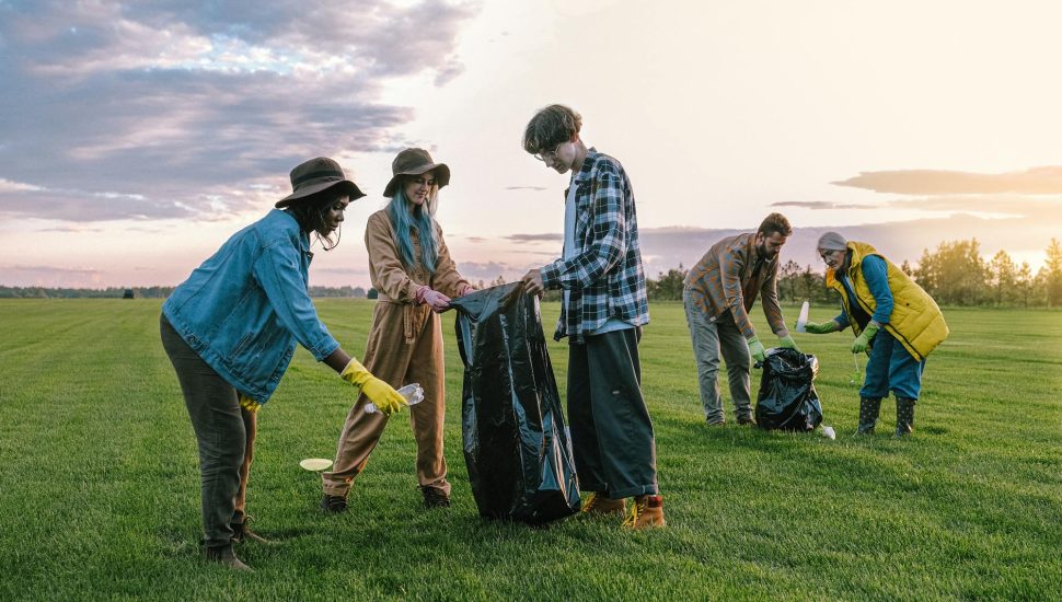 volunteers collecting trash on green grass field