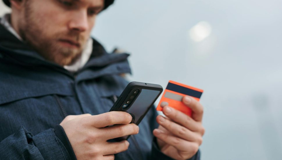serious man paying online purchases using smartphone on street