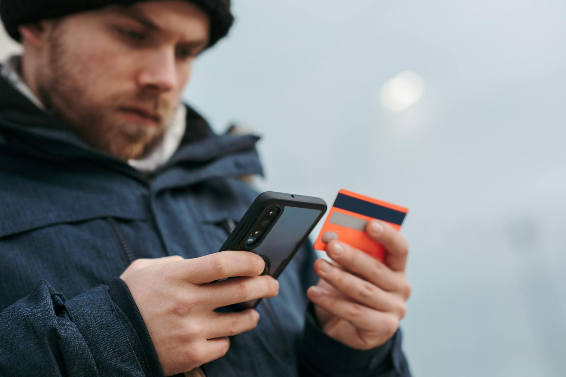 serious man paying online purchases using smartphone on street