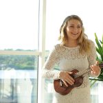 woman wearing white floral dress playing ukulele