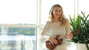 woman wearing white floral dress playing ukulele