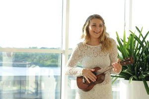 woman wearing white floral dress playing ukulele