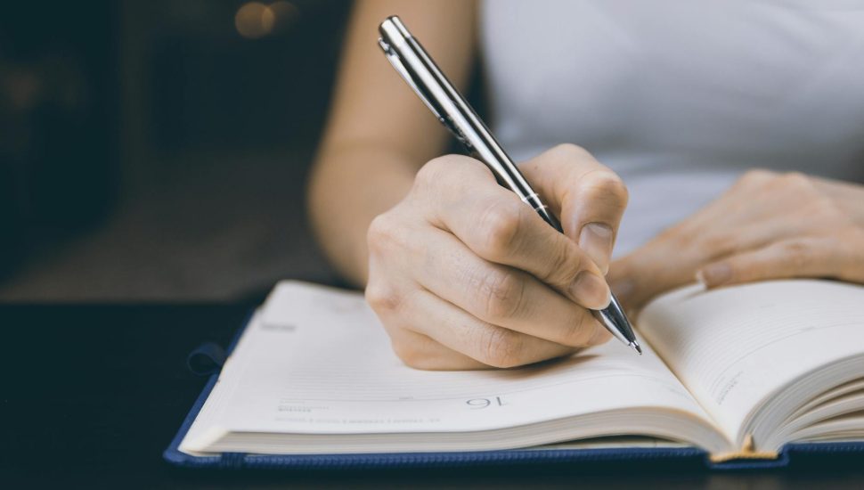 photo of person writing on notebook