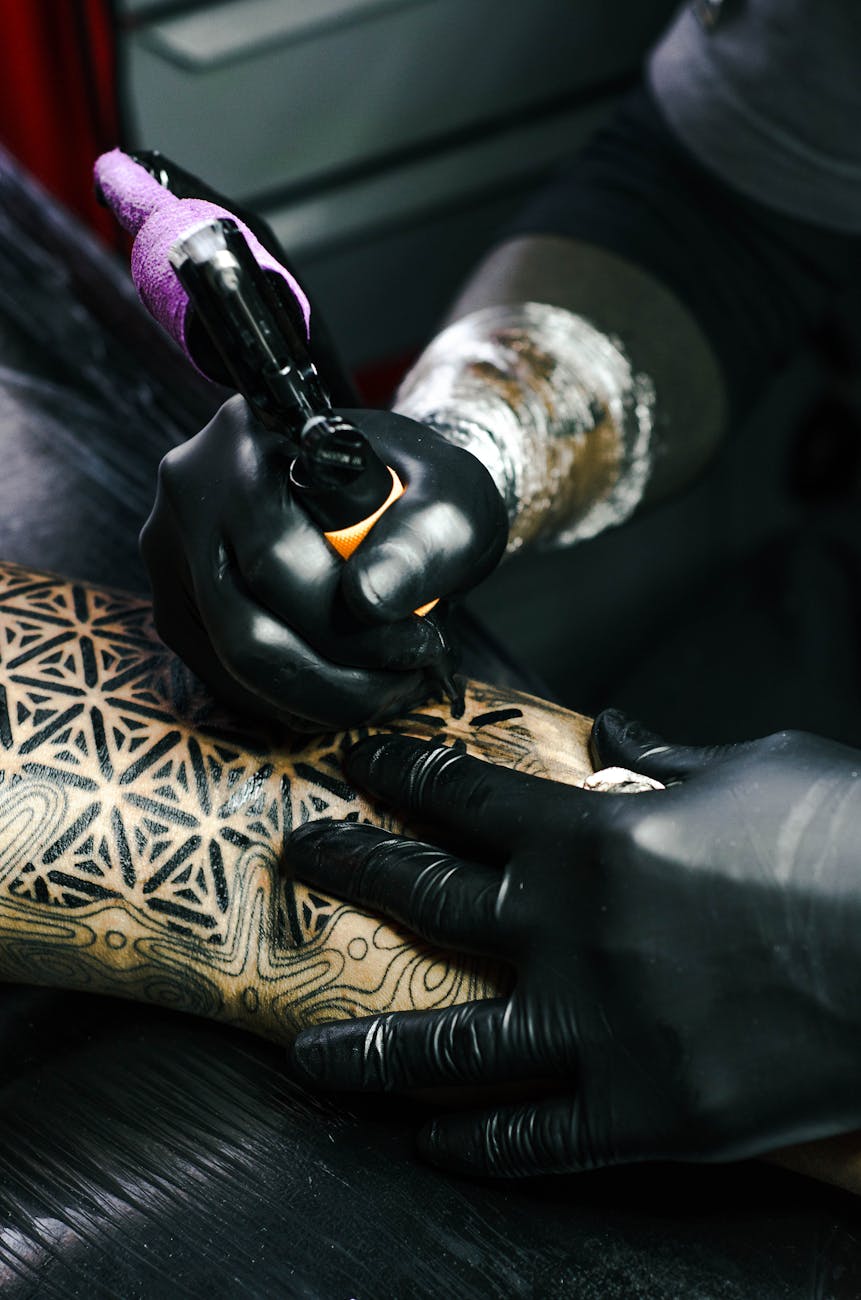 selective focus photography of tattoo artist drawing a tatoo
