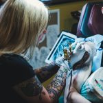 woman tattooing man on his right arm