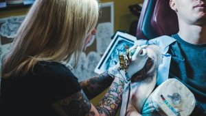 woman tattooing man on his right arm