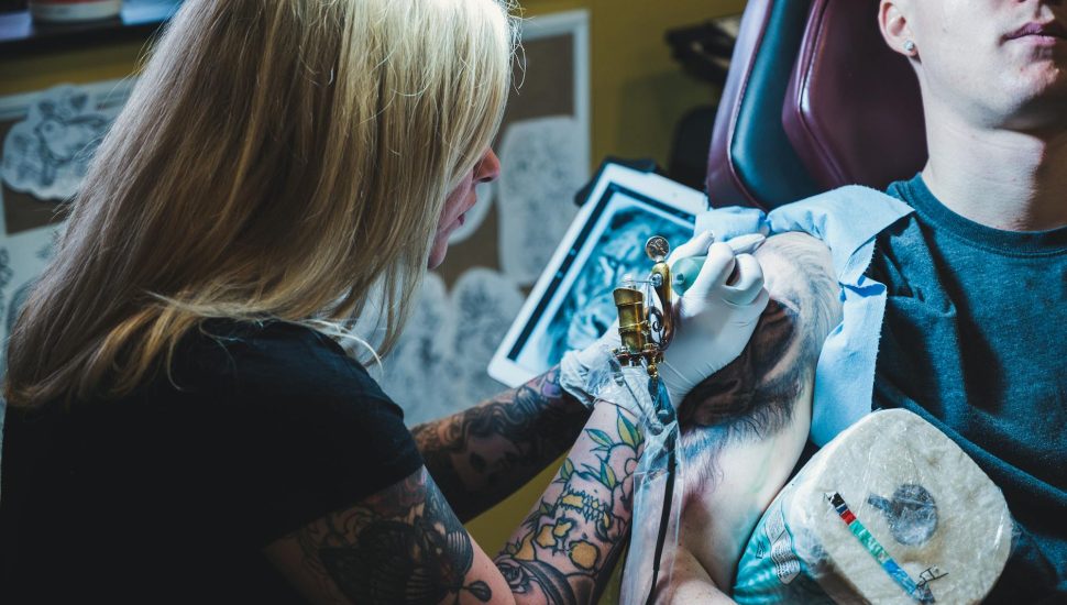 woman tattooing man on his right arm